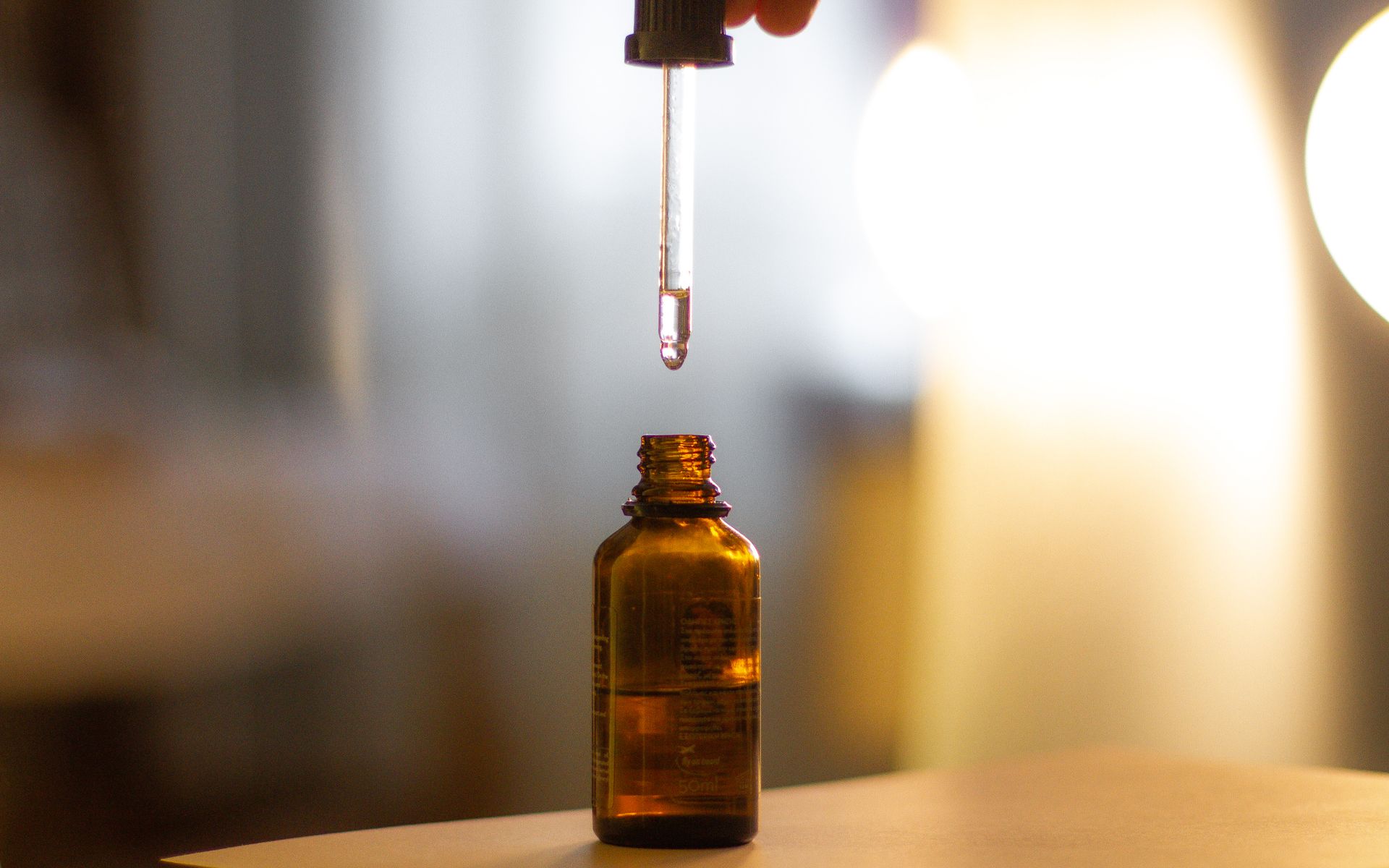 Amber glass serum bottle with a dropper on warm stone