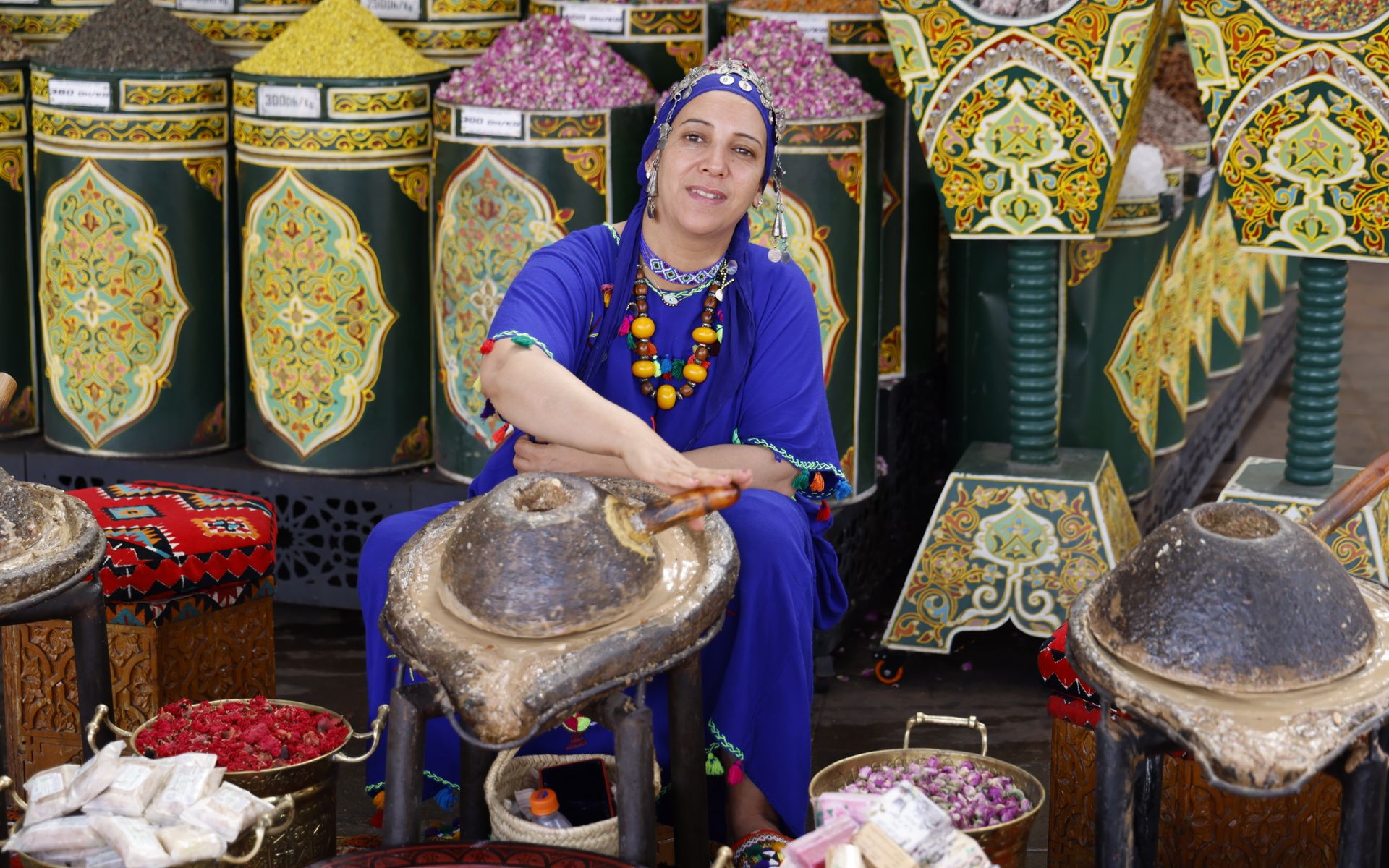 A woman grinding argan kernels on a stone press